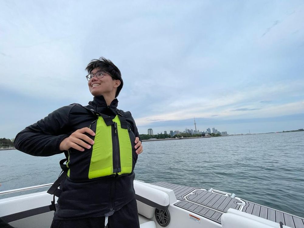 Liam on a boat, Toronto skyline behind him